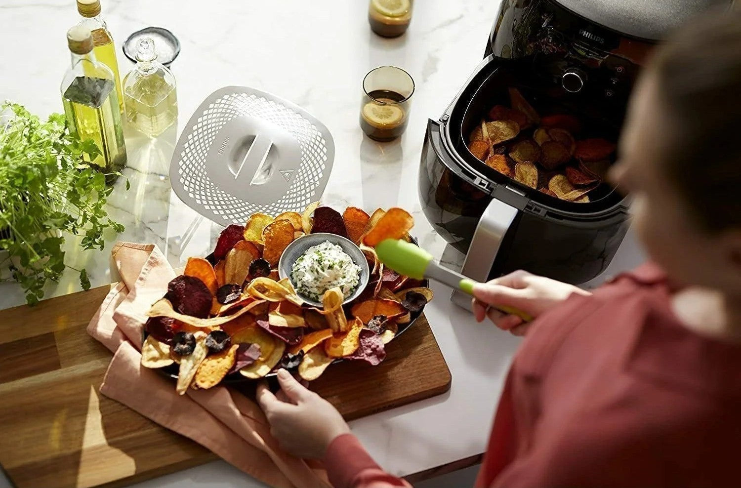 Bovenaanzicht van een open Ninja Airfryer MAX PRO met een hele geroosterde kip en aardappeltjes in de mand. Een persoon haalt de lade eruit, wat illustreert dat de 6,2 liter mand ruimte biedt aan een royale portie (bijvoorbeeld een hele kip).