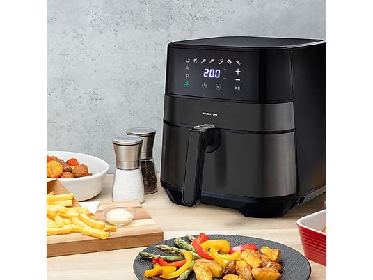 De Ninja Airfryer MAX PRO op een aanrecht, omringd door diverse bereide gerechten – gebak, gegrilde vis met groenten, geroosterd vlees en salade – wat de veelzijdigheid van de 6-in-1 kookprogramma’s (Air Fry, Max Crisp, Bakken, Roosteren, Opwarmen en Drogen) laat zien.